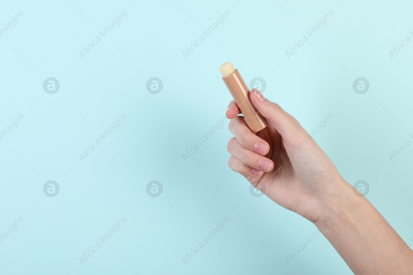 Photo of Woman with lip balm on light turquoise background, closeup. Space for text