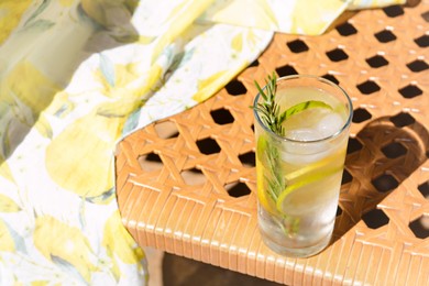 Photo of Tasty refreshing lemonade on wicker bench, space for text. Summer drink