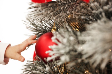 Photo of Cute little baby touching Christmas ball indoors, closeup