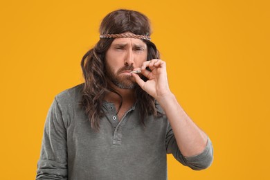 Photo of Hippie man smoking cigarette on orange background