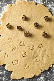 Photo of Making shortcrust pastry. Raw dough and cookie cutters on grey table, top view