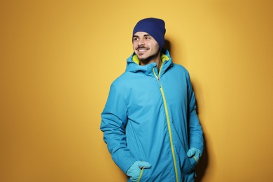 Photo of Young man wearing warm clothes on color background. Ready for winter vacation