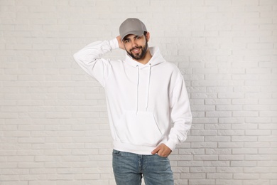 Photo of Portrait of young man in sweater at brick wall. Mock up for design
