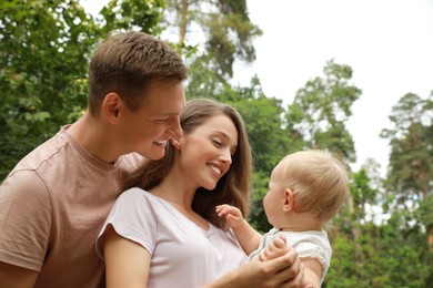 Photo of Parents with their cute baby spending time together outdoors. Happy family
