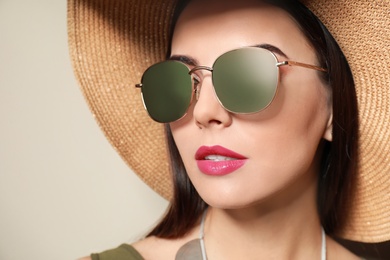 Photo of Beautiful woman in stylish sunglasses and hat on beige background