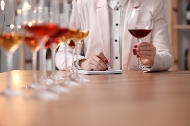 Photo of Sommelier tasting different sorts of wine at table indoors, closeup