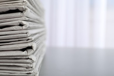 Photo of Stack of newspapers on grey table, space for text. Journalist's work