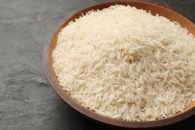 Photo of Raw basmati rice in bowl on black table, closeup