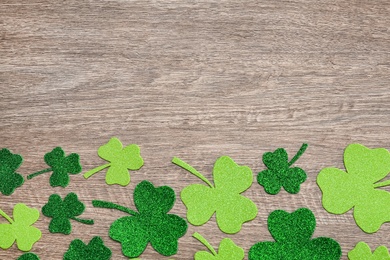 Photo of Decorative clover leaves on grey wooden table, flat lay with space for text. Saint Patrick's Day celebration