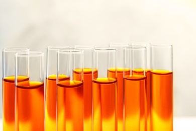 Photo of Closeup view of many test tubes with orange liquid on color background