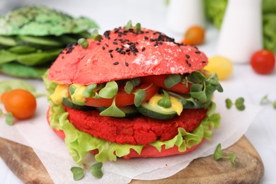 Photo of Tasty pink vegan burger with vegetables, patty and microgreens on white table, closeup