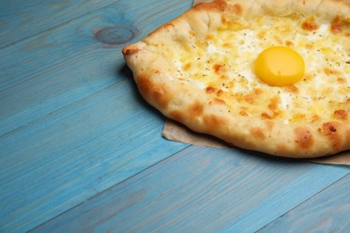 Photo of Fresh homemade khachapuri with cheese and egg on light blue wooden table. Space for text