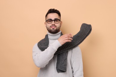 Photo of Handsome man in knitted scarf on beige background