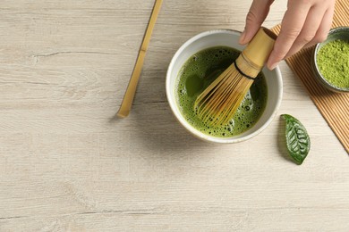 Photo of Woman preparing matcha tea at wooden table, top view. Space for text