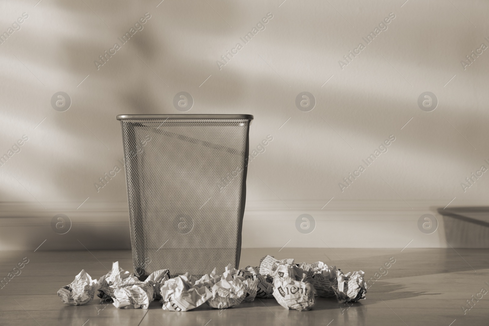 Photo of Metal bin and crumpled paper near white wall indoors, space for text. Rubbish recycling