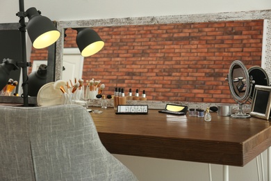 Photo of Cosmetic and brushes on dressing table in makeup room