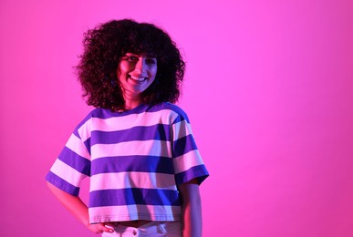 Photo of Beautiful young woman posing on color background in neon lights. Space for text