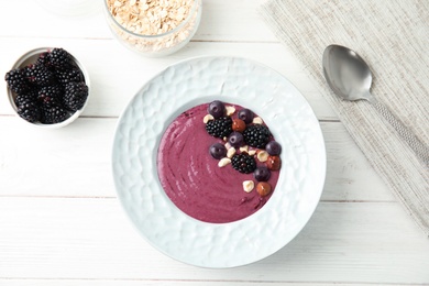 Photo of Flat lay composition with plate of tasty acai smoothie on wooden table