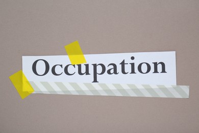 Word Occupation attached with yellow adhesive tape on grey background