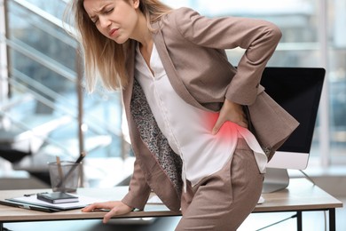 Image of Woman suffering from pain in lower back at workplace in office