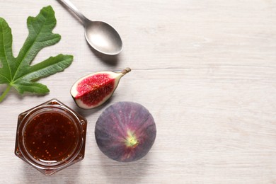 Photo of Jar of tasty sweet jam and fresh figs on white wooden table, flat lay. Space for text