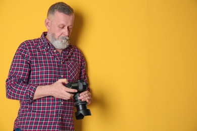 Photo of Mature male photographer with camera on color background