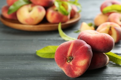 Photo of Fresh ripe donut peaches on grey wooden table, closeup. Space for text