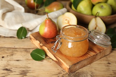 Photo of Delicious pear jam and fresh fruits on wooden table. Space for text