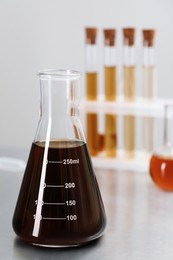 Photo of Conical flask with brown liquid on table