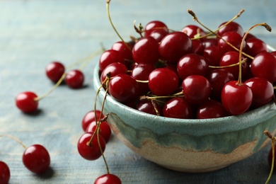 Photo of Bowl of delicious cherries on blue wooden table, closeup view. Space for text