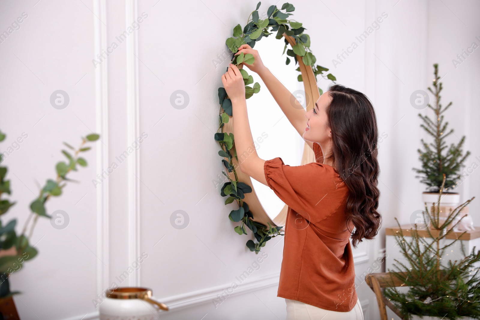 Photo of Woman decorating mirror with eucalyptus branches at home. Space for text