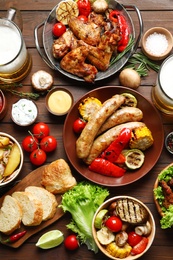 Photo of Delicious meal served for barbecue party on wooden table, flat lay