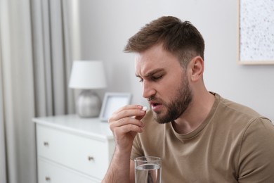 Photo of Man taking pill against migraine at home