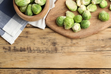 Fresh Brussels sprouts on wooden table, flat lay. Space for text