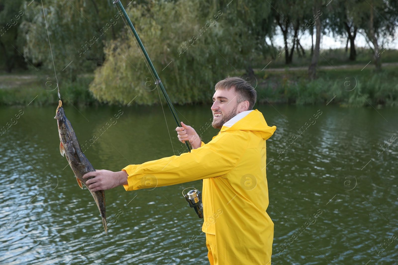 Photo of Man with rod and catch fishing at riverside. Recreational activity