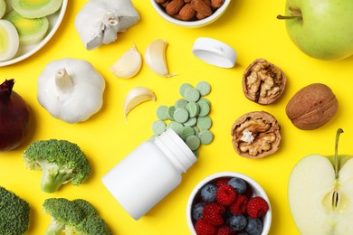 Photo of Food and bottle of prebiotic pills on yellow background, flat lay