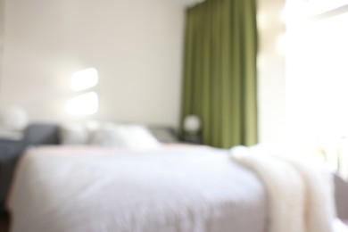 Photo of Blurred view of large bed near window in room
