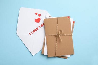 Photo of Love letter and stack of envelopes on light blue background, flat lay