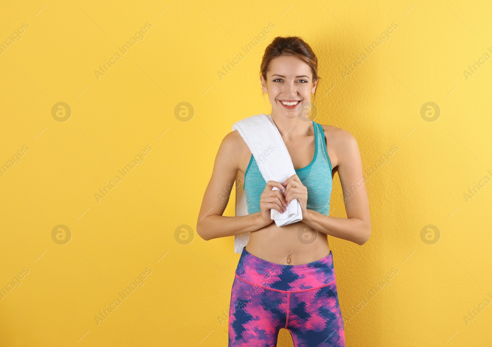 Photo of Beautiful young woman in sportswear with towel on color background