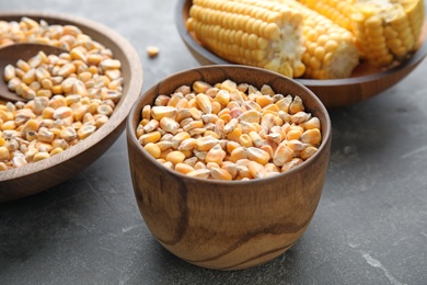 Photo of Bowls with dried corn kernels on grey table