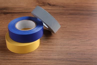Photo of Colorful insulating tapes on wooden table. Space for text