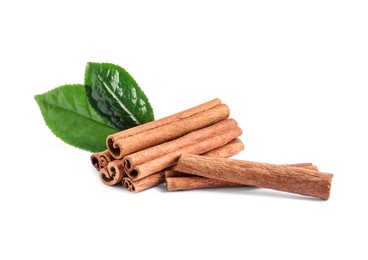 Photo of Aromatic cinnamon sticks and green leaves isolated on white