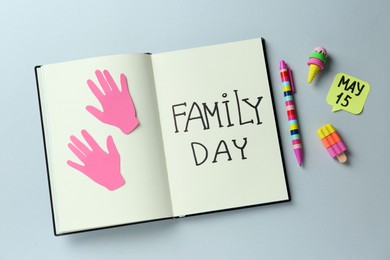 Photo of Notebook with text Family Day May, paper hand cutouts and stationery on light grey background, flat lay