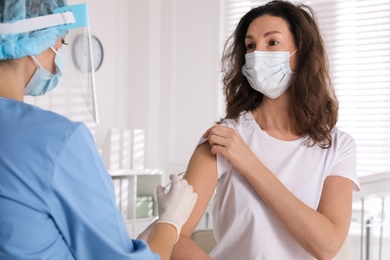 Photo of Doctor vaccinating mature woman against Covid-19 in clinic