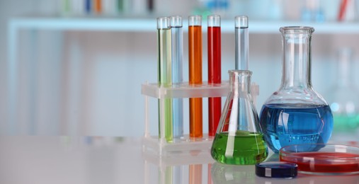 Photo of Laboratory analysis. Different glassware with liquids on white table against blurred background. Space for text