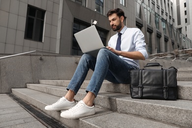 Photo of Handsome man working with laptop on city street