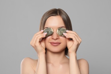 Photo of Young woman with tea bags on light grey background. Eye skin care