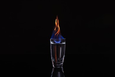 Photo of Flaming vodka in shot glass on black background