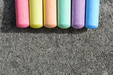 Photo of Colorful chalk sticks on asphalt, flat lay. Space for text