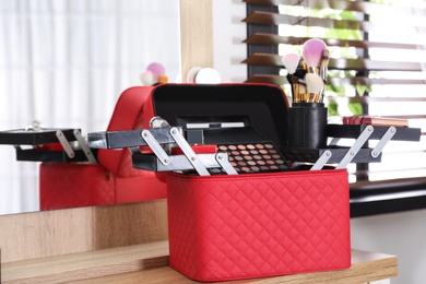 Photo of Beautician case with professional makeup products and tools on wooden dressing table